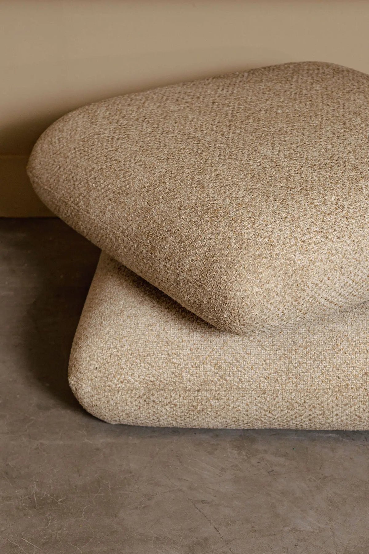 Draaibare Aro Poef Taupe Opulence van PTMD met zachte bekleding en ronde vorm op een lichte houten vloer.