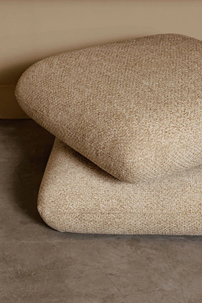 Draaibare Aro Poef Taupe Opulence van PTMD met zachte bekleding en ronde vorm op een lichte houten vloer.